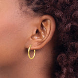 20 mm slim huggie hoop earrings in solid 14K yellow gold shown on ear