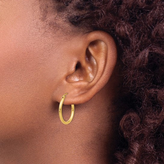 20 mm slim huggie hoop earrings in solid 14K yellow gold shown on ear