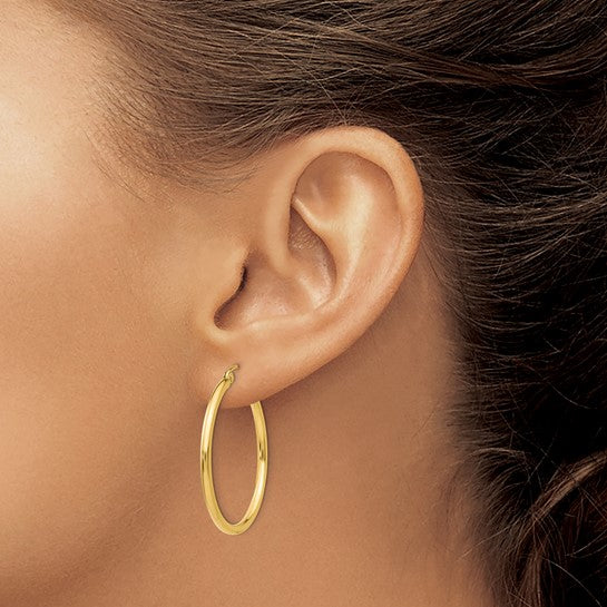 30 mm slim hoop earrings in solid 14K yellow gold shown on ear